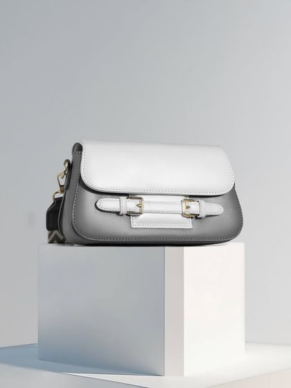 A two-tone grey and white bag sitting on a white pedestal. This is a classic, clean product shot that highlights the bag's minimalist design.