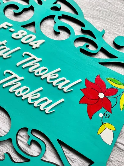 A close-up look at the hand-painted flowers on this teal wooden nameplate. These small details are what make each piece unique and personal.