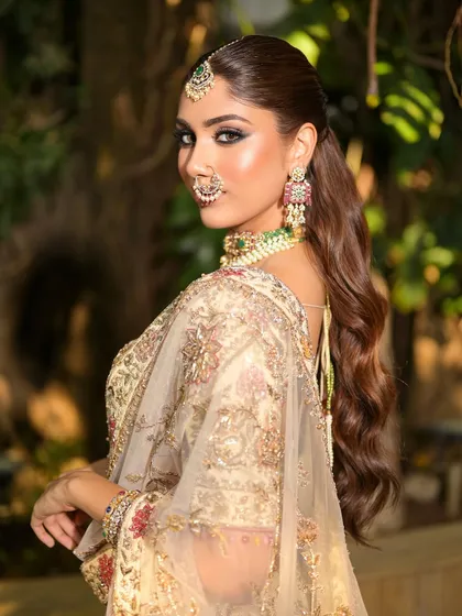 A beautiful over-the-shoulder shot, showing off the wavy ponytail and the elegant back of the blouse. The makeup is flawless from every angle.