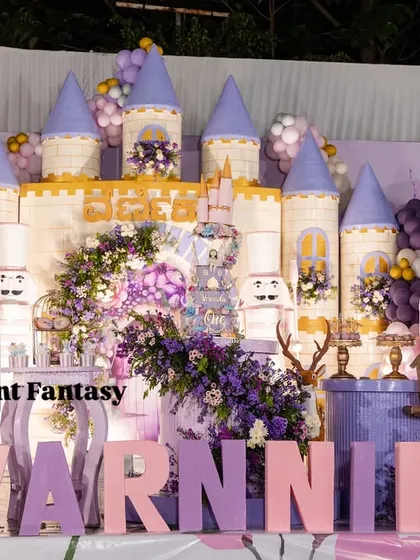 A closer view of Varnnika's fairyland stage, highlighting the intricate castle backdrop, the large "VARNNIKA" letters, and the adorable fairy and deer props.