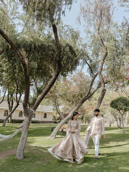 A romantic walk in the park for the couple. The bride's pastel outfit looks beautiful in the natural outdoor setting.