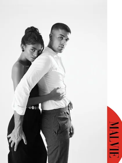 A black and white couple's portrait for a Malvie magazine editorial. The simplicity of the high-key setup and monochrome palette emphasizes the connection and the lines of their bodies. It’s intimate and modern.