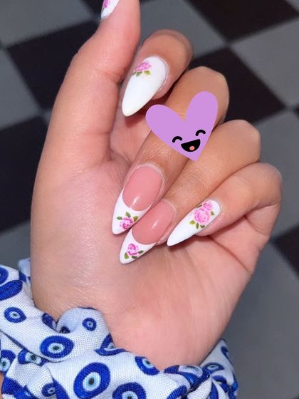 A beautiful white French manicure with delicate pink floral art. This student's work is a perfect example of combining classic techniques with artistic flair.
