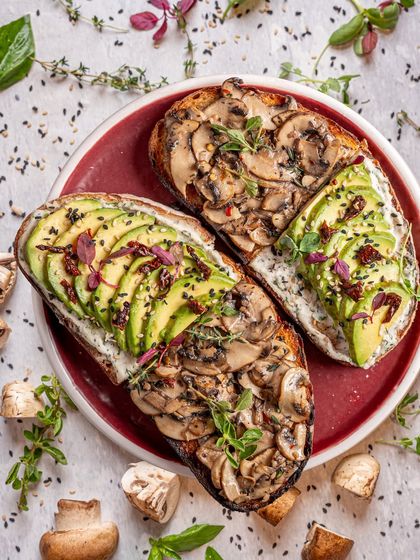A beautiful flatlay of avocado and mushroom toast. The vibrant colors and artful arrangement of ingredients make a simple dish look like a gourmet meal. This is perfect for a cafe that prides itself on fresh, beautiful food.
