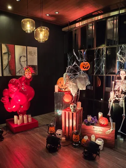 A creative and spooky decor installation for a Halloween event. A red balloon sculpture and an illuminated skeleton create an artistic and modern take on classic Halloween decorations.
