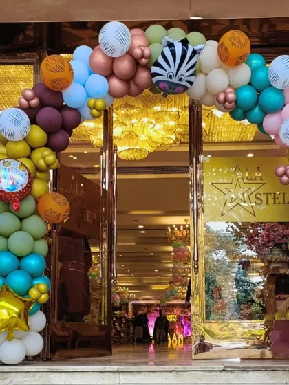 A grand entrance balloon arch for a jungle party, using a mix of colors and animal print balloons to set the theme.
