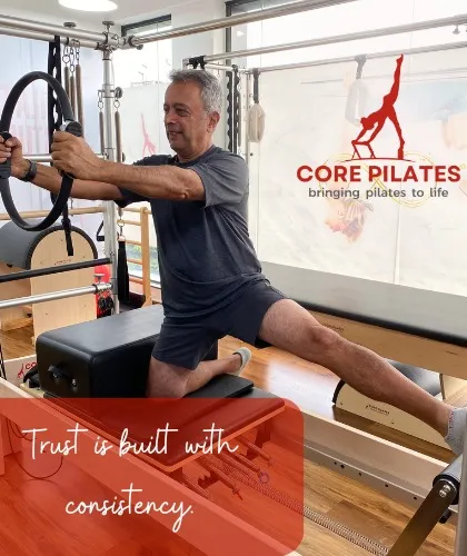 We incorporate a variety of accessories to keep workouts dynamic and effective. Here, a client uses the Magic Circle to engage his inner thighs and core while performing a side leg press on the reformer, adding a new level of challenge.