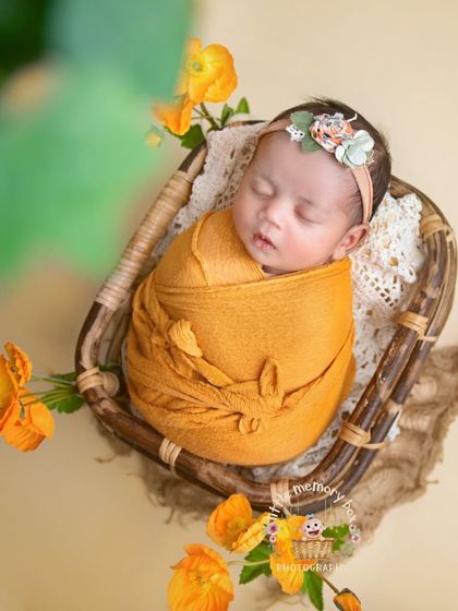 This is the final image from the behind-the-scenes video, showing the baby peacefully asleep in a basket, surrounded by vibrant orange flowers.