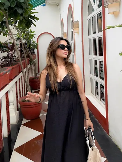 A throwback shot showing a black maxi dress styled for summer. The setting in a bright, architecturally interesting corridor adds to the vacation aesthetic.