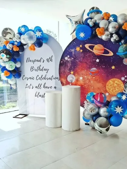 A cosmic celebration for a 9th birthday. The decor features a galaxy-print backdrop and a balloon arrangement with planet and astronaut details.