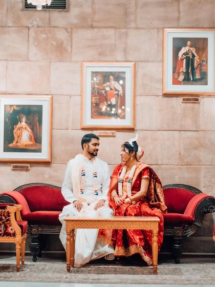A formally posed portrait of a Bengali couple, seated in a regal setting, capturing the elegance and cultural richness of their wedding.