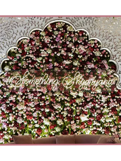 A beautifully designed photo backdrop for an engagement, featuring an arch-shaped wall of red, pink, and white roses with a custom neon sign. It’s the perfect spot for capturing memories.