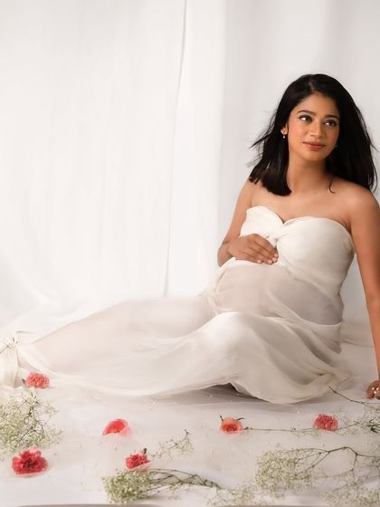 A dreamy, ethereal setup with soft white fabric and scattered flowers. This portrait is all about capturing the gentle, delicate side of pregnancy.