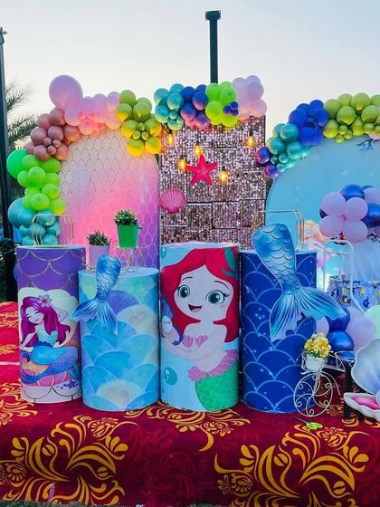 An outdoor mermaid theme setup against a beautiful sunset. The vibrant colors and themed props like the seahorse and seashell create a magical scene.