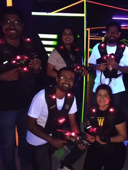 A team smiles for the camera during their laser tag game, part of a corporate team outing.