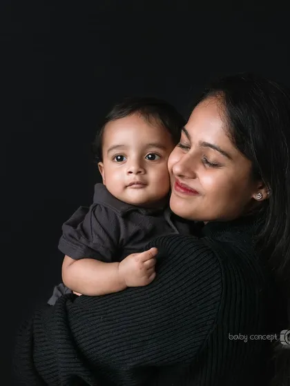A mother's gentle embrace. This portrait focuses on the secure and loving bond between a mother and her baby, captured with soft lighting against a simple dark backdrop.