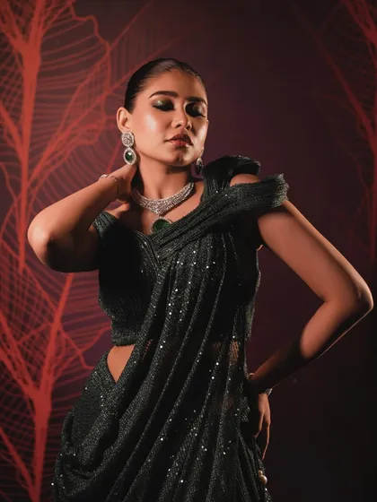 The complete look is powerful and elegant. The sleek hair and dramatic makeup are a perfect match for the structured saree.