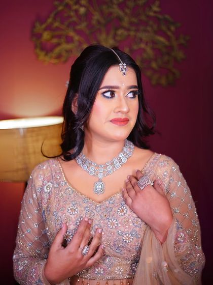 A close-up portrait highlighting the diamond necklace and soft, neutral makeup tones.