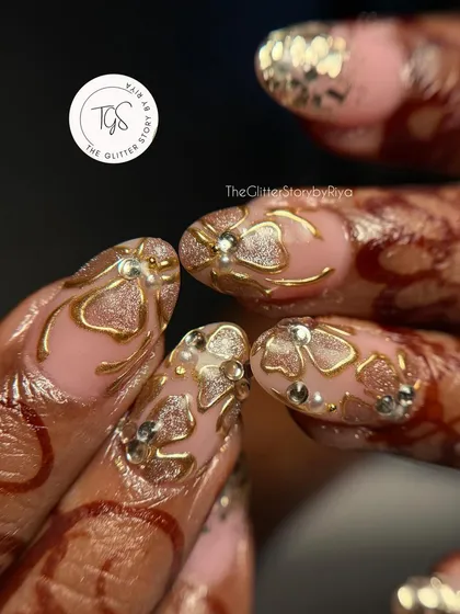 An incredibly detailed bridal set designed to match the bride's henna. It features intricate 3D gold patterns with crystal accents over a glittery pink base.