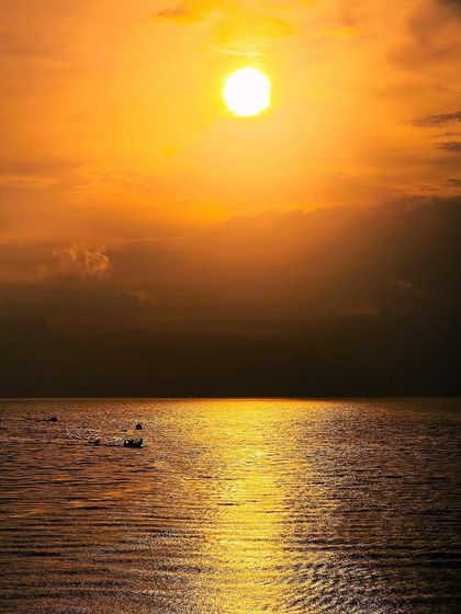 A golden sunset over the water in Lakshadweep, with small boats silhouetted against the light. A classic, beautiful moment of coastal life.