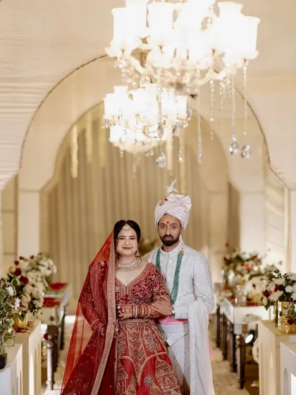 A beautiful portrait of the couple during their wedding ceremony, framed by an elegant white archway and sparkling chandeliers.