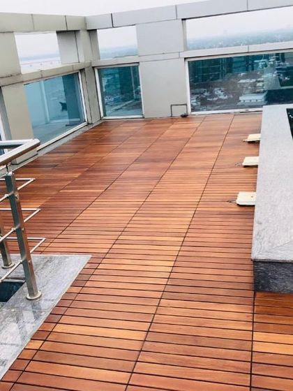 The IPE decking provides a warm, natural contrast to the cool tones of the water and the modern glass railings of the building.