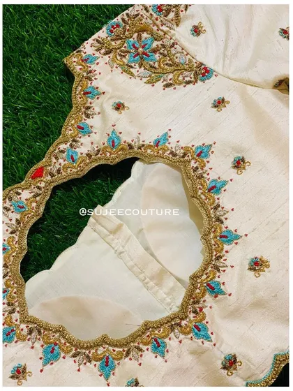 The back of the cream blouse, featuring a deep cutout with a scalloped edge. The entire back neckline is framed with the same beautiful turquoise and red floral embroidery.