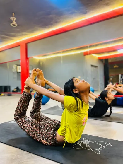 Students practicing Dhanurasana (Bow Pose) in a group class, all working on their back flexibility together.