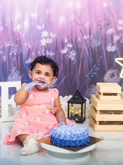 A classic cake smash moment, with the birthday girl enjoying her first taste of cake during her pre-birthday photoshoot.