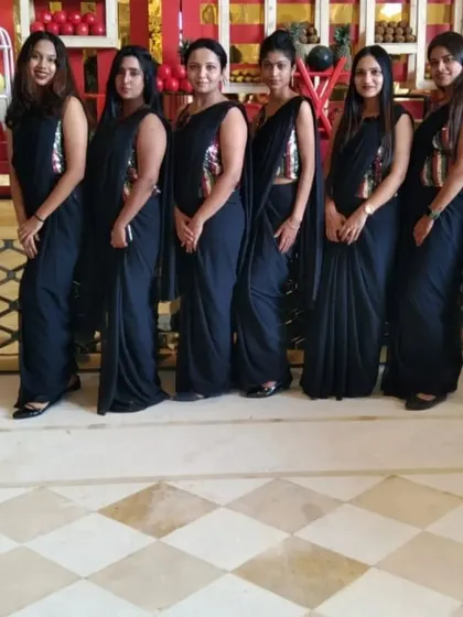 A team of my female hostesses in elegant black sarees with sequined blouses, perfect for upscale corporate events and weddings.