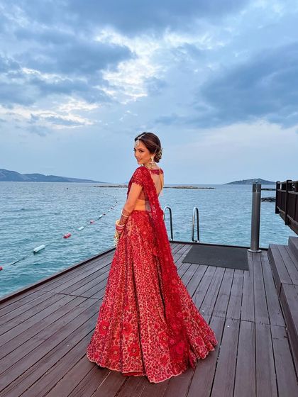 A full-length shot of the bride, her elegant updo complementing the dramatic backdrop of the sea.