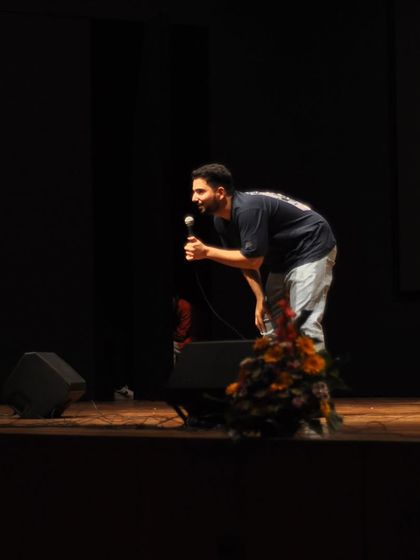 Samay Raina leaning in to deliver a punchline, a classic moment from his live stand-up show.