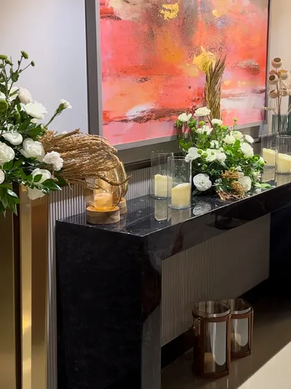 A console table styled for an event. We used tall gold vases, candles, and floral arrangements to create a stunning focal point that complements the client's artwork.