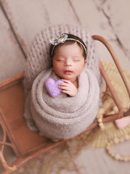 A touch of lavender. This sweet baby is holding a tiny felt heart, wrapped in a soft grey knit on a miniature sleigh prop.