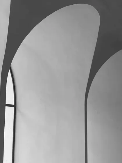 A black and white abstract shot focusing on the beautiful play of light and shadow created by the intersecting arches and the narrow window.