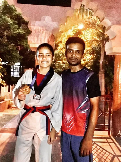 A smiling champion with her medal. This student, a red-black belt, demonstrates the long-term dedication that leads to success in Taekwondo.