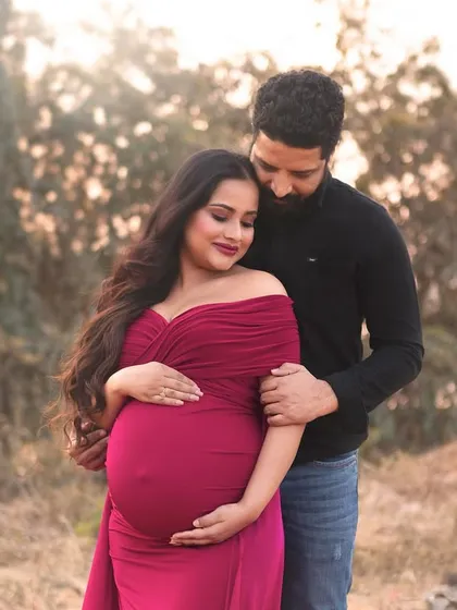 An intimate outdoor couple's portrait captured in the soft evening light. The rich color of her gown contrasts beautifully with the natural background, creating a romantic and moody frame.