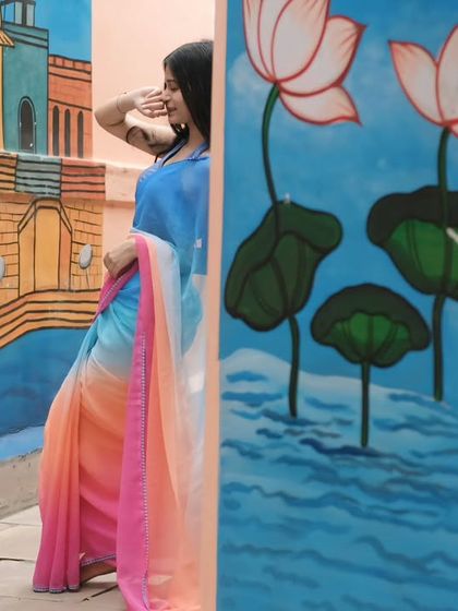 A living painting on the walls of Varanasi. The subject's colorful saree complements the street art, creating a beautiful fusion of fashion and local culture.