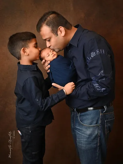 The bond between a father, his son, and his new baby is truly special. Here, dad and big brother share a gentle kiss with the newest family member, a moment of pure love and protection.