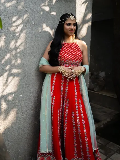 A full-length shot of the bride's Mehendi outfit, a vibrant red jumpsuit.