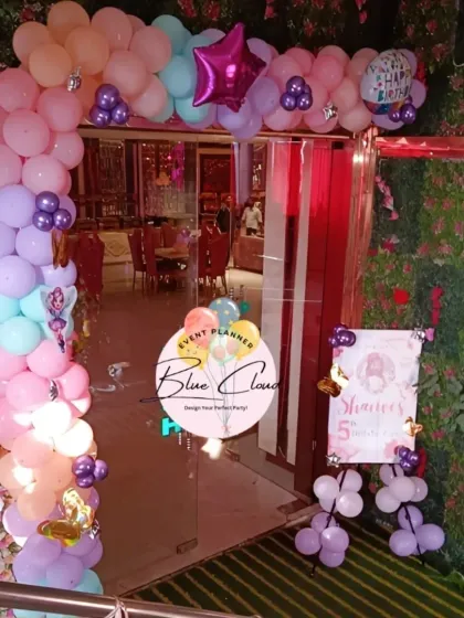 A beautiful pastel balloon arch decorating the entrance to a party venue.