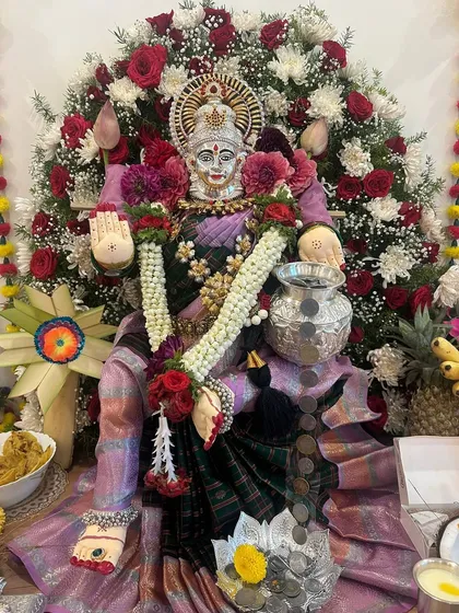 A close-up showing the intricate details of the saree and the offerings of coins and flowers to the Goddess of wealth.