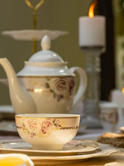 A close-up of a teacup from Vigneto's floral collection, with a teapot softly blurred in the background. This shot creates a warm and inviting atmosphere, focusing on the experience of enjoying a cup of tea.