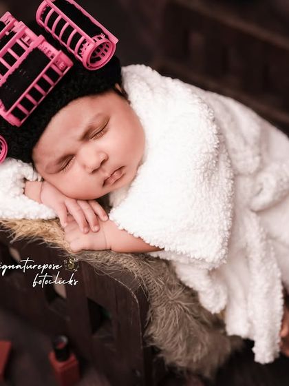 Getting pampered after a long nine months. This newborn is enjoying her spa day, complete with hair rollers and a cozy robe. We love creating these humorous and adorable setups.