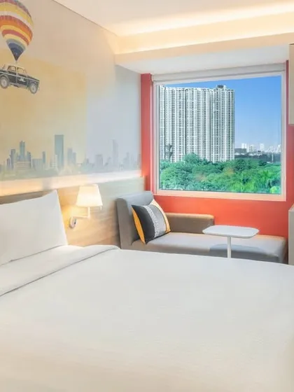 A guest room at the Ibis Hotel in Thane, where modern, efficient design is enhanced by a custom wall mural depicting the Mumbai cityscape, reflecting our approach of infusing local culture into our interiors.
