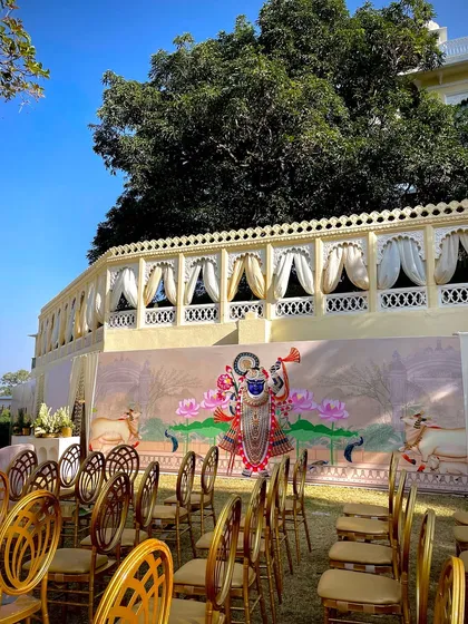 The seating arrangement for a daytime wedding, with a beautiful hand-painted Pichwai art backdrop depicting Shrinathji. I love incorporating local art forms to give the wedding a unique and culturally rich feel.