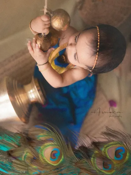 A playful moment as baby Radha tries to lift a brass pot. This unique angle adds a dynamic and creative feel to the portrait.