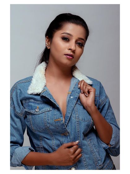 A cool and confident studio portrait featuring a denim jacket with a shearling collar. The direct gaze and simple styling create a strong, modern look.