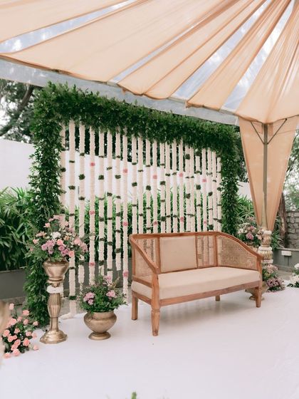 For an intimate and earthy engagement, I chose this elegant cane sofa. The backdrop is a screen of hanging tuberose garlands, framed by lush greenery, creating a look that is both minimalist and traditionally inspired.