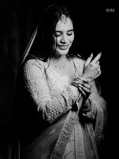 An elegant black and white portrait of the bride-to-be, capturing her gentle smile and the intricate details of her outfit.